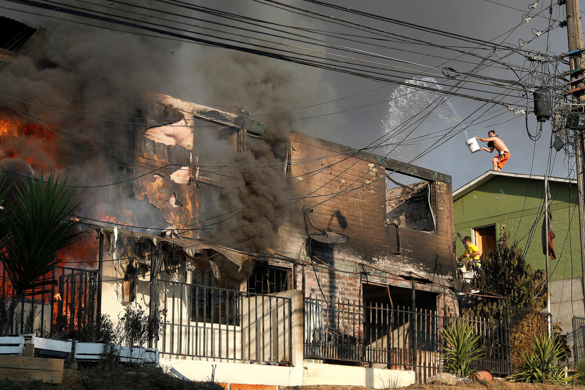 Des habitants tentent d’éteindre un feu dévastant une maison à Vina del Mar, au Chili, le 3 février 2024. 