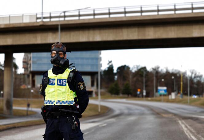 Un policier avec un masque à gaz devant le siège du service de renseignement suédois Sapo, au nord de Stockholm, le 23 février 2024.
