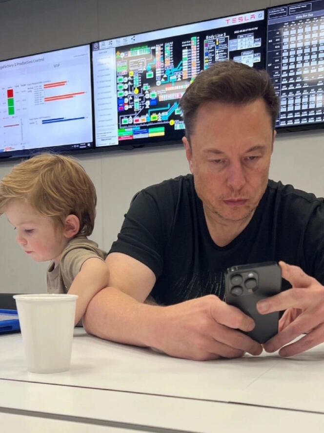 Elon Musk utilisant son téléphone, pendant que son fils X Æ A-XII regarde une tablette, en 2023, dans les locaux de Tesla, à Austin (Texas, Etats-Unis).