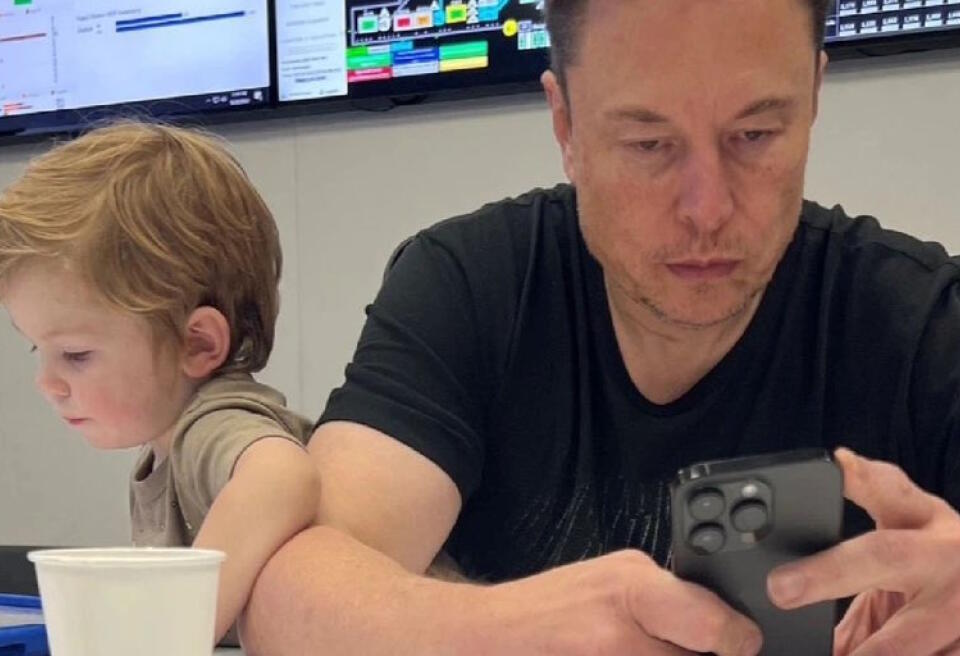 Elon Musk regardant son téléphone, pendant que son fils X Æ A-Xii regarde une tablette.