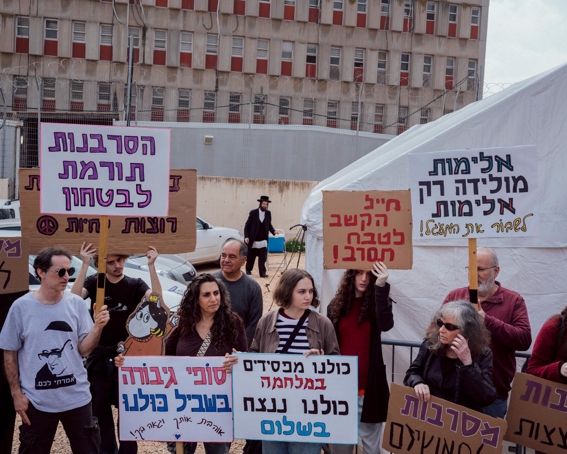 Sofi Orr (center) appears at the Israeli army's call-up for military service surrounded by her family and supporters, February 25, 2024, Tel-HaShomer base, Kiryat Ono, Israel. On the placards, "Refusing contributes to security", "Sofi is a heroine to us", "Listen to the refuseniks", "We are all losers in the war", "Violence brings violence".