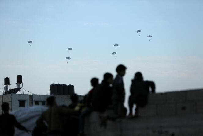 Los palestinos observan cómo el ejército estadounidense realiza su primer lanzamiento de ayuda humanitaria sobre la ciudad de Gaza, el 2 de marzo de 2024. 