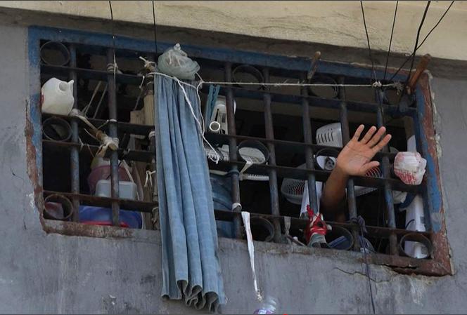 Cette capture d’écran de l’AFP-TV montre une personne agitant la main à travers les barreaux d’une cellule de la prison principale de Port-au-Prince, le 3 mars 2024, après l’évasion de plusieurs milliers de détenus.