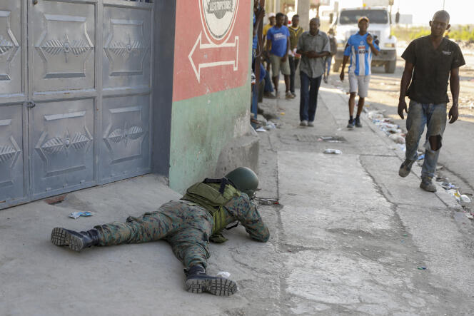 Des piétons passent devant un soldat gardant la zone de l’aéroport international à Port-au-Prince, Haïti, lundi 4 mars 2024. Des membres de gangs ont échangé des coups de feu avec la police et les soldats autour de l’aéroport au cours d’une série d’attaques sur les sites du gouvernement.