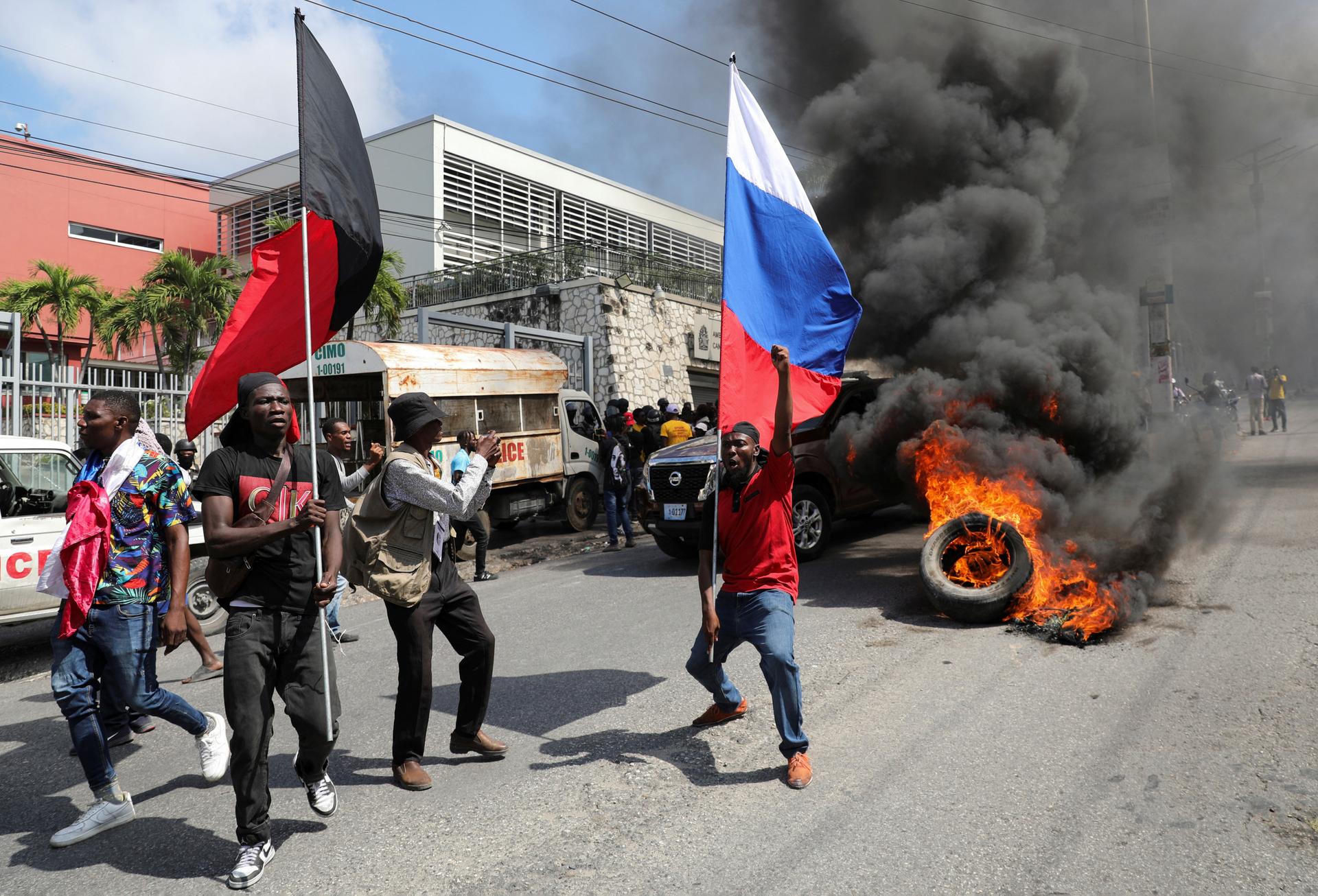A demonstrator, holding a Russian flag to call for foreign intervention, taking part in a protest calling for the resignation of Haitian Prime Minister Ariel Henry outside the Canadian Embassy, in Port-au-Prince, Haiti, February 25, 2024.