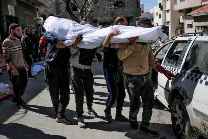 Men carry the body of a Palestinian killed during the distribution of aid during which Israeli forces opened fire, in Gaza City on February 29, 2024.