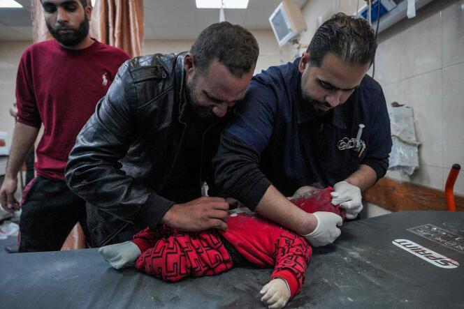 A Palestinian doctor examines a child pulled from the rubble of a house after an Israeli bombardment in Deir al-Bala in the central Gaza Strip on March 12, 2024.