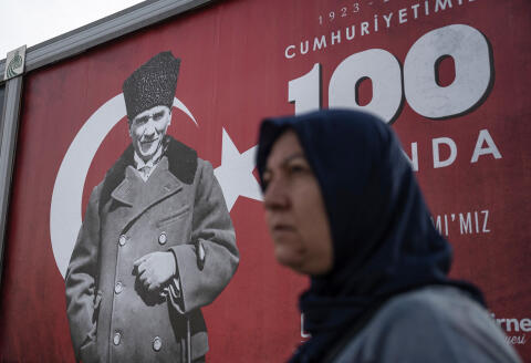 A woman walks past banner with the portrait of Mustafa Kemal Ataturk (L) ahead of celebrations marking the 100th anniversary of the Turkish Republic in Edirne, western Turkey on October 25, 2023. (Photo by Ozan KOSE / AFP)