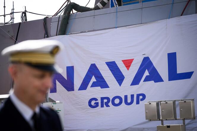 An officer walks in front of a Naval Group logo at the Naval Group's shipyard in Lorient, western France, on October 4, 2023.  