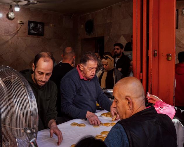 Palestinians buy "qatayef," semolina pancakes made for Ramadan, at the Damascus Gate market in East Jerusalem, March 11, 2024.