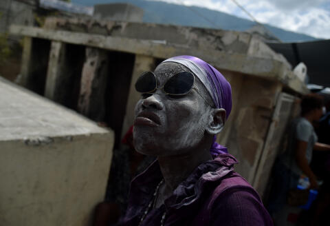 A voodoo devotee in the role of a spirit known as a Gede is seen during ceremonies honoring the Haitian voodoo spirit of Baron Samdi and Gede on the Day of the Dead in the National Cemetery, in Port-au-Prince, Haiti, on November 2, 2017. Voodoo believers and devotees offer candles, alcohol and food. The Day of the Dead is celebrated on the first two days of November during All Saints and All Souls Day. (Photo by HECTOR RETAMAL / AFP)
