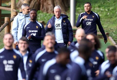 France's head coach Didier Deschamps (back C) and France's forward Kylian Mbappe (back R) speak together as the team arrives for a training session as part of the team's preparation for upcoming friendly football matches, in Clairefontaine-en-Yvelines on March 20, 2024. (Photo by FRANCK FIFE / AFP)