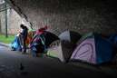 Young homeless migrants next to tents under the Sully bridge in the east of Paris on February 10, 2024.