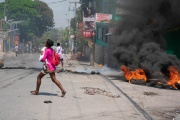 Une femme, bébé au bras, tente d’échapper aux tirs armés, à Port-au-Prince, à Haïti, le 20 mars 2024. 