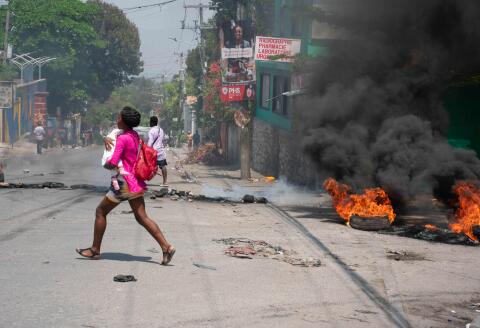 Une femme, bébé au bras, tente d’échapper aux tirs armés, à Port-au-Prince, à Haiti, le 20 mars 2024.