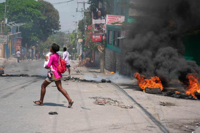 Une femme, bébé au bras, tente d’échapper aux tirs armés, à Port-au-Prince, à Haïti, le 20 mars 2024. 