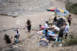 The Sanchez Chagua family on the shores of the river Rimac, while they clean the clothes of a recently deceased family member. The river attracts many people to its shores for necessity and traditional reasons as river water is often used in cleansing rituals. Ate, Lima, Peru. 06.03.2024