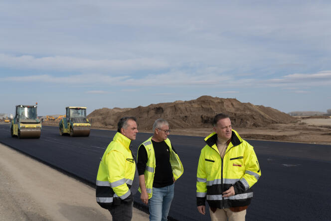Guido Retter, directeur général de Retter Projectmanagement (à droite) et Efthymios Anagnostou, chef de projet (à gauche), discutent avec un collègue alors que l’asphalte est coulé sur le chantier de construction de l’autoroute A7, à l’extérieur de Ploiesti, en Roumanie, le 10 mars. 2024.