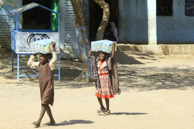 Des enfants transportent des paquets d’aide humanitaire dans une école où leurs familles ont trouvé refuge, près de la ville de Gedaref, au Soudan, le 6 mars 2024.