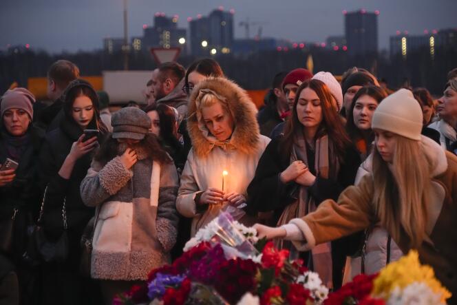 Des personnes déposent des fleurs et des bougies au lendemain de l’attaque qui a fait plus de 130 morts, près du Crocus City Hall, en périphérie de Moscou, le 23 mars 2024.