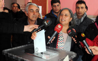 Gulten Kisanak (Center R), the Peace and Democracy party candidate campaigning to be Mayor of Diyarbakir, casts her ballot in Diyarbakir on March 30, 2014, during municipal elections in Turkey ahead of a presidential vote in six months and parliamentary polls next year. Turkey's Premier Recep Tayyip Erdogan, embattled by protests and corruption scandals, faced a crucial popularity test today when over 50 million eligible voters cast their ballots in local elections. More than 50 million voters were to cast their ballots for mayors and local assemblies at almost 200,000 pollings stations, pitting Erdogan's Islamic-rooted Justice and Development party against secular, nationalist and other groups. AFP PHOTO / ILYAS AKENGIN (Photo by ILYAS AKENGIN / AFP)
