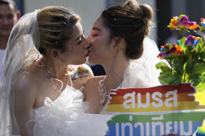 Des femmes s’embrassant en tenant une affiche en faveur de la légalisation du mariage homosexuel, lors de la Gay Pride, le 4 juin 2023 à Bangkok, en Thaïlande. 