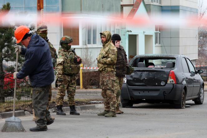 Des volontaires d'une unité d'autodéfense près d'une voiture endommagée suite à une attaque aérienne, à Belgorod, en Russie, le 22 mars 2024.