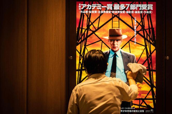 Un employé nettoie un écran montrant une publicité pour « Oppenheimer » à Tokyo, le 29 mars 2024, jour de la sortie du film dans les salles japonaises.
