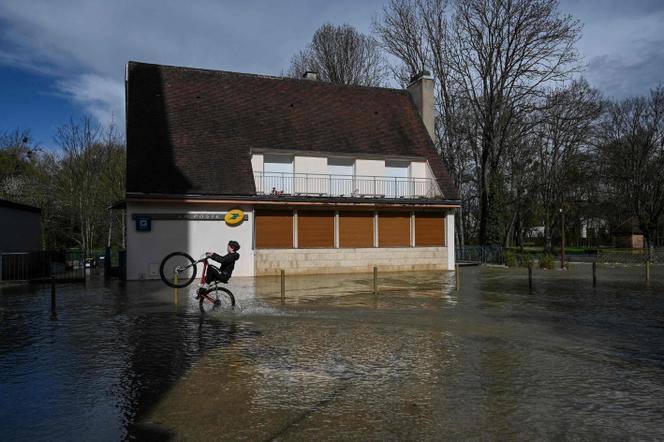 Un jeune homme sur son vélo pendant une inondation à Velars-sur-Ouche, en Bourgogne, en 2024. 