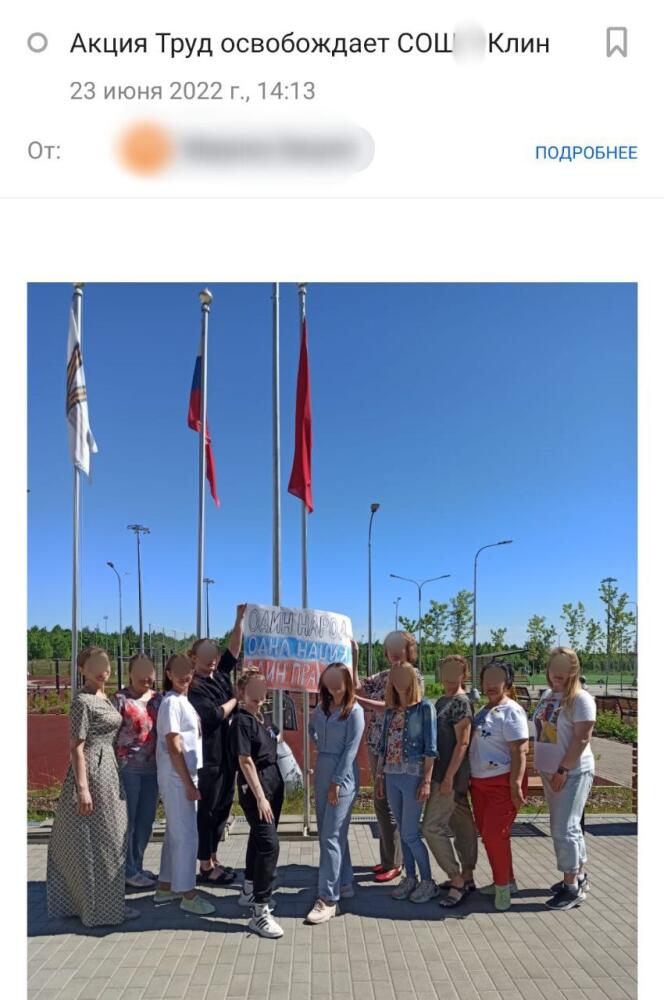 Des enseignants de la ville de Klin (Russie) posent devant un drapeau proclamant « Un peuple, une nation, un leader », dans le cadre de l'action « Le travail libère » de l'artiste Vladislav Bokhan, en juin 2022.