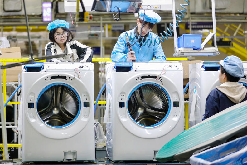 Employees work on a washing machine production line at a factory for Chinese home appliances and consumer electronics company Haier in Qingdao, in eastern China's Shandong province on February 18, 2024. (Photo by AFP) / China Out