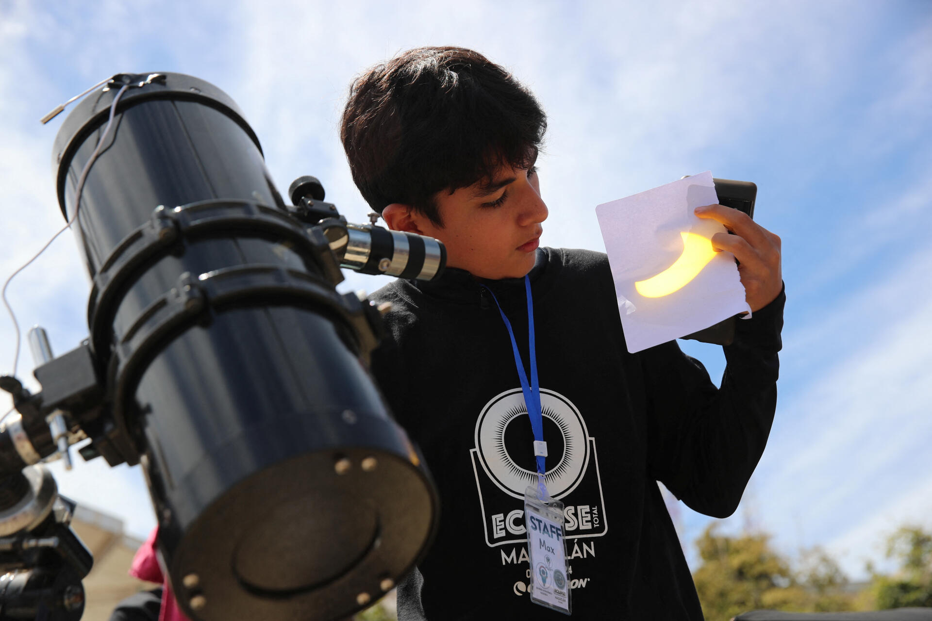 Un adolescent regarde l'éclipse solaire projetée sur papier depuis son télescope à Mazatlan, Mexique, le 8 avril 2024.