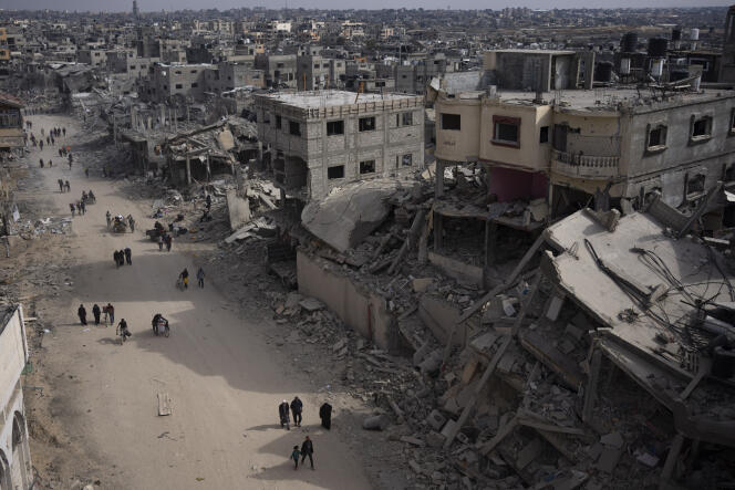 Palestinos caminan en medio de la destrucción causada por una ofensiva aérea y terrestre israelí en Khan Younes, en el sur de la Franja de Gaza, el lunes 8 de abril de 2024.