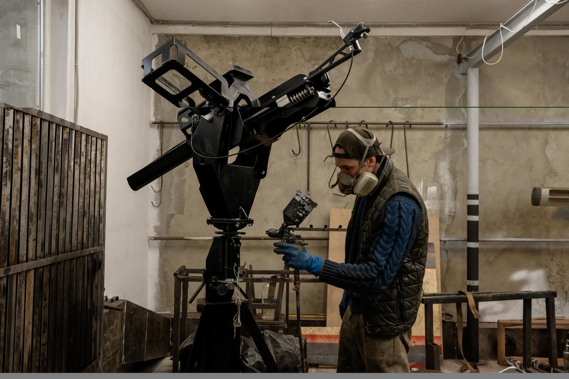Stanislav Skrinnik paints the frame of an anti-aircraft machine gun, in a theater set design workshop which has been converted for military weapons production, in Odesa, Ukraine, February 29, 2024.