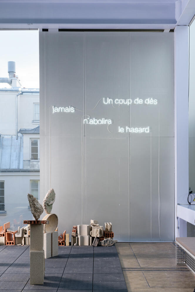 Vue de l’exposition « Coming Soon. En attendant demain », à Lafayette Anticipations, à Paris. Au sol, « Balance » (2024), de Bridget Polk. Au mur, « … Après Stéphane Mallarmé » (2008), de Cerith Wyn Evans.
