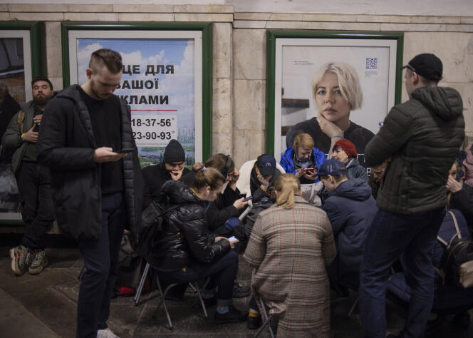 Des Ukrainiens à l’abri dans une station de métro cherchent à obtenir des informations avec leur téléphone, à la suite d’explosions entendues dans le centre de Kiev, en Ukraine, le 25 mars 2024.