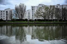 (FILES) A photo shows the banks of the Saint-Denis canal and apartment buildings in le Franc Moisin neighbourhood of Saint-Denis, a northern Paris suburb, on March 13, 2024. Free places, passage of the flame, fan zones, initiatives are multiplying in Seine-Saint-Denis to keep the promise of a popular festival of the Paris Olympic Games in this poor neighbourhood which hosts a large part of the hardships. “One in 10 residents will be able to attend an event or the opening ceremony,” said Stéphane Troussel, the president of the department who announced that 180,000 tickets will be offered to the neighbourhood, which has 1.65 million inhabitants. (Photo by JULIEN DE ROSA / AFP)