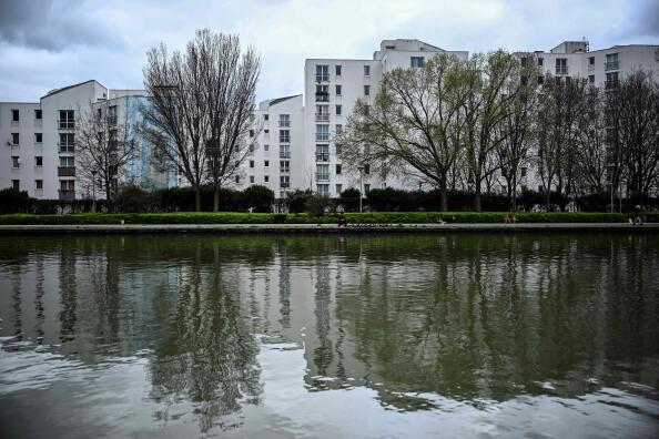 (FILES) A photo shows the banks of the Saint-Denis canal and apartment buildings in le Franc Moisin neighbourhood of Saint-Denis, a northern Paris suburb, on March 13, 2024. Free places, passage of the flame, fan zones, initiatives are multiplying in Seine-Saint-Denis to keep the promise of a popular festival of the Paris Olympic Games in this poor neighbourhood which hosts a large part of the hardships. “One in 10 residents will be able to attend an event or the opening ceremony,” said Stéphane Troussel, the president of the department who announced that 180,000 tickets will be offered to the neighbourhood, which has 1.65 million inhabitants. (Photo by JULIEN DE ROSA / AFP)