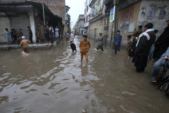 Des jeunes pataugent dans une rue inondée par de fortes pluies à Peshawar, Pakistan, lundi 15 avril 2024. 