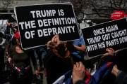Anti-Trump protesters hold signs outside the New York City courthouse on the day the ex-president's trial begins, April 15, 2024.
