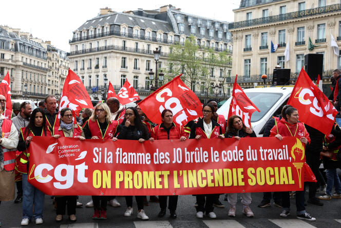 Manifestantes vestidos con chalecos sindicales y banderas de la CGT participan en una marcha con antorchas para denunciar las condiciones laborales de los empleados durante los Juegos Olímpicos de París 2024, en la Place de l'Opéra, en París, el 15 de abril de 2024.