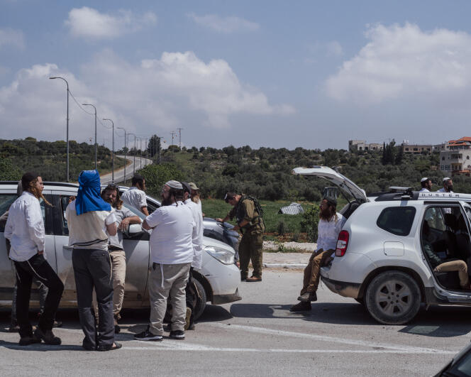 Des colons israéliens encadrés par des militaires bloquent l'entrée du village palestinien de Tourmous Aya, menant également au village d'Al-Moughaïr, en Cisjordanie occupée, samedi 13 avril 2024. 