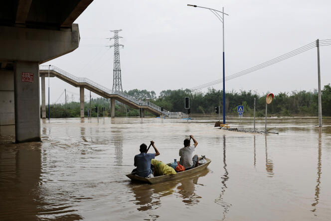Des habitants du village de Xiashahe, à Qingyuan, dans la province du Guangdong, en Chine, le 22 avril 2024, font avancer un bateau sur les eaux de crue à la suite de fortes pluies. 