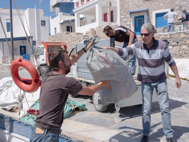 Angelos Vavlekis remet un sac de déchets en plastique, ramassés sur les plages d’Amorgos à l’initiative de l’association Fisher, à son président, Michalis Krosman, à Katapola (Grèce), le 4 avril 2024.