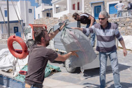 Angelos Vavlekis hands a bag of plastic trash, collected from the beaches around Amorgos on initiative of the Fisher association, to it's president Michalis Krosman - at Katapola.