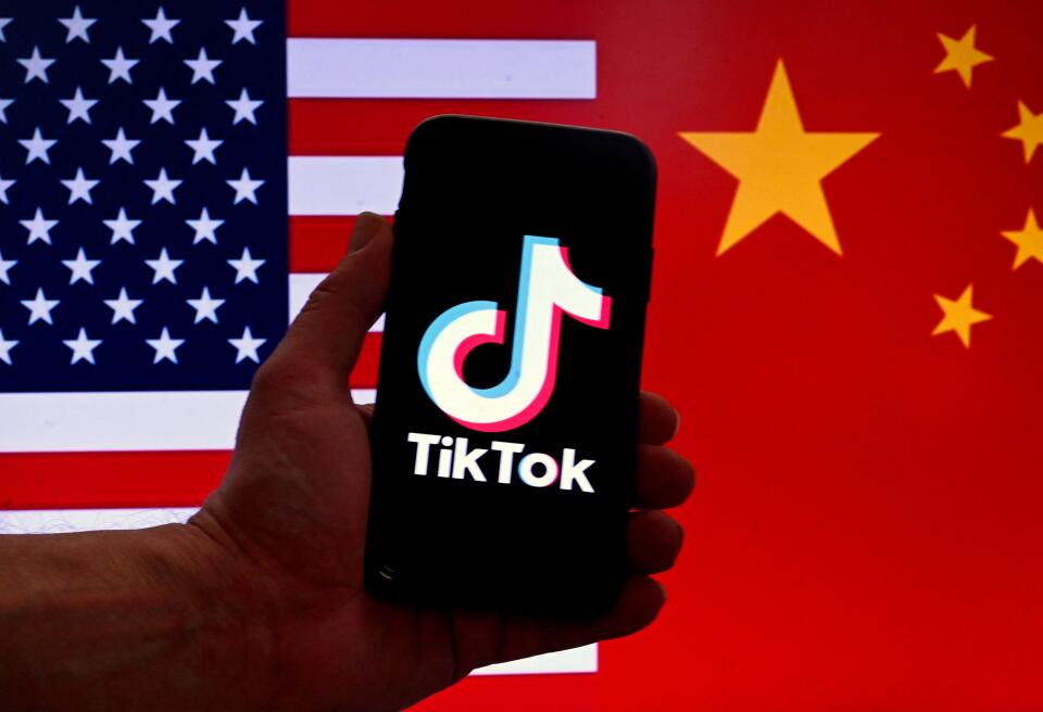 (FILES) In this photo illustration the social media application logo for TikTok is displayed on the screen of an iPhone in front of a US flag and Chinese flag background in Washington, DC, on March 16, 2023. The US Senate on Tuesday approved legislation requiring the wildly popular social media app TikTok to be divested from its Chinese parent company ByteDance or be shut out of the American market. The measure was part of a $95 billion foreign aid package, including military assistance to Ukraine, Israel and Taiwan, which has now cleared Congress and heads to President Joe Biden's desk. (Photo by OLIVIER DOULIERY / AFP)