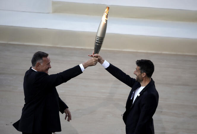 Le président du Comité olympique hellénique, Spyros Capralos, et Tony Estanguet, président du Comité d’organisation des JO 2024, tiennent la flamme olympique, le 26 avril 2024 au stade panathénaïque à Athènes, en Grèce.