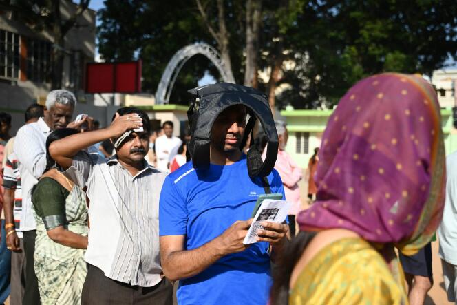 Des électeurs indiens se protègent du soleil en attendant de pouvoir voter, le 26 avril 2024, à Bengaluru.
