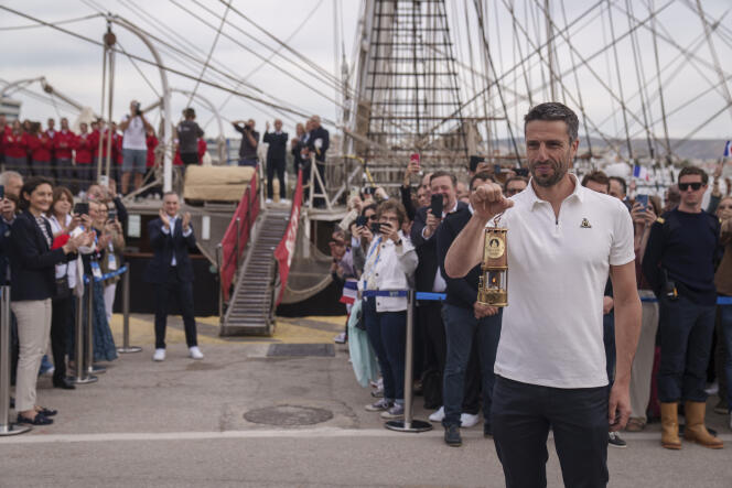 Tony Estanguet, président du Comité d’organisation des Jeux de Paris 2024, tient la lanterne qui contient la flamme olympique, devant le « Belem », au port du Pirée, en Grèce, le 27 avril 2024.