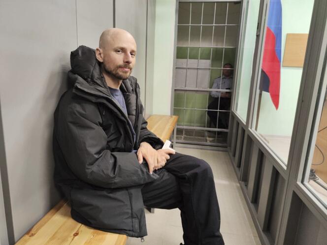 Le journaliste russe Sergueï Kareline dans la cage vitrée réservée aux prévenus dans une salle d'audience où il comparaît après son arrestation pour « extrémisme ».  Oblast de Mourmansk (Russie), 27 avril 2024.